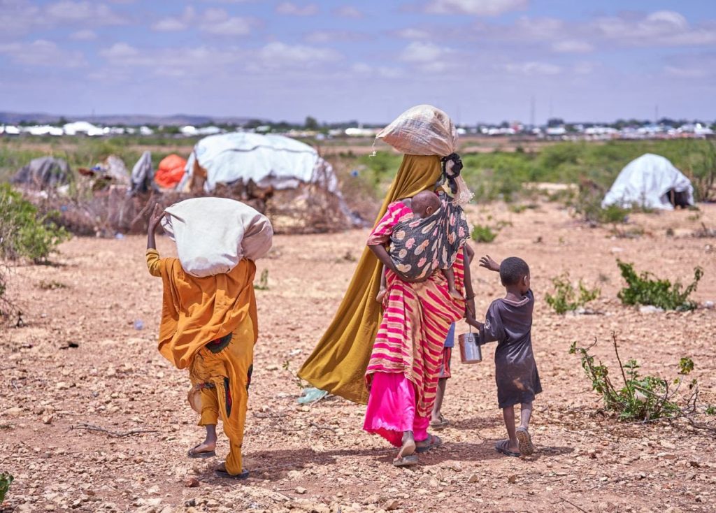 A Somali mother and her children displaced by flooding search for a place to take shelter among other families who have already found refuge on higher ground. Photo: IOM/ Ismail Abdihakim Ismail