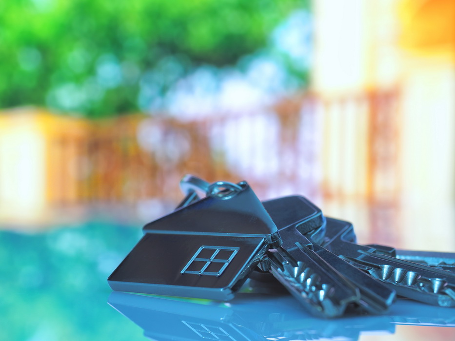 House Keys With House Figure On Desk Out Of Focus Background