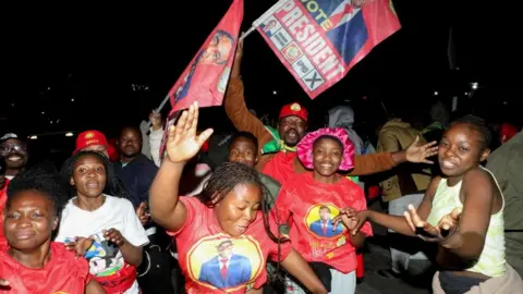Reuters Les partisans du président zambien Hakainde Hichilema font la fête, vêtus d'un T-short avec son umage.