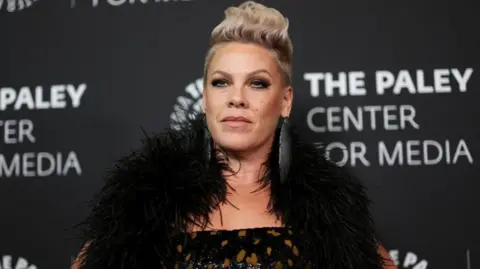 Reuters Pink porte une tenue noire à plumes sur un tapis rouge.