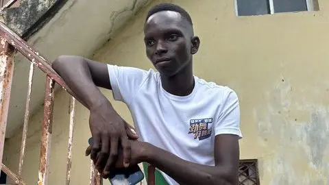 Un jeune homme en T-shirt blanc menant sur la rampe rouillée d'un escalier